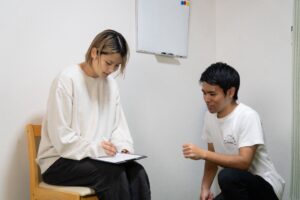 理学療法士が姿勢と動作を評価するカウンセリング風景(チェックリストを用いた問診と可動域テストの様子)